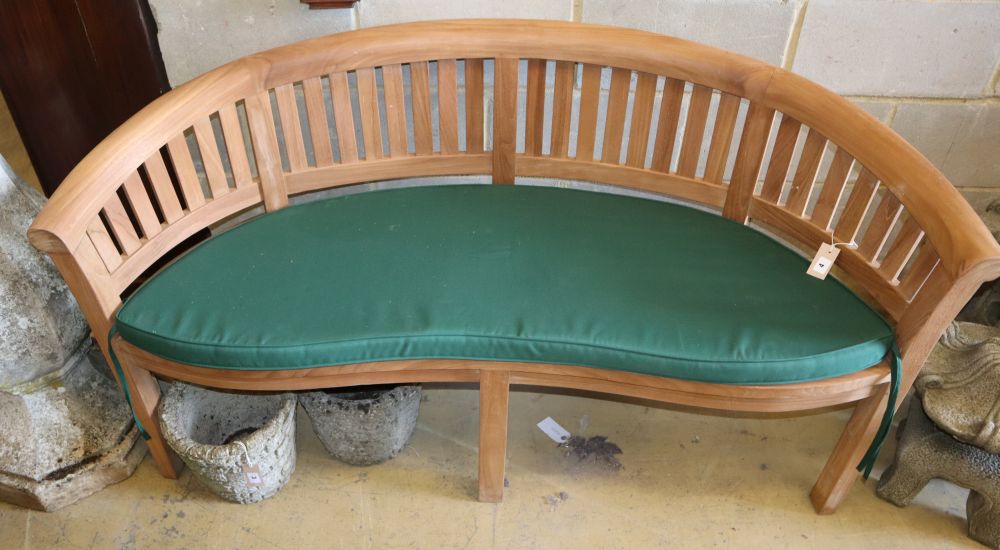 A teak garden banana bench with cushion seat, W.160cm, D.54cm, H.85cm